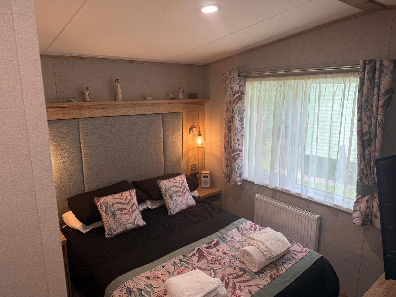 The main bedroom: a double bed with a sage panel headboard and lit wall lamps